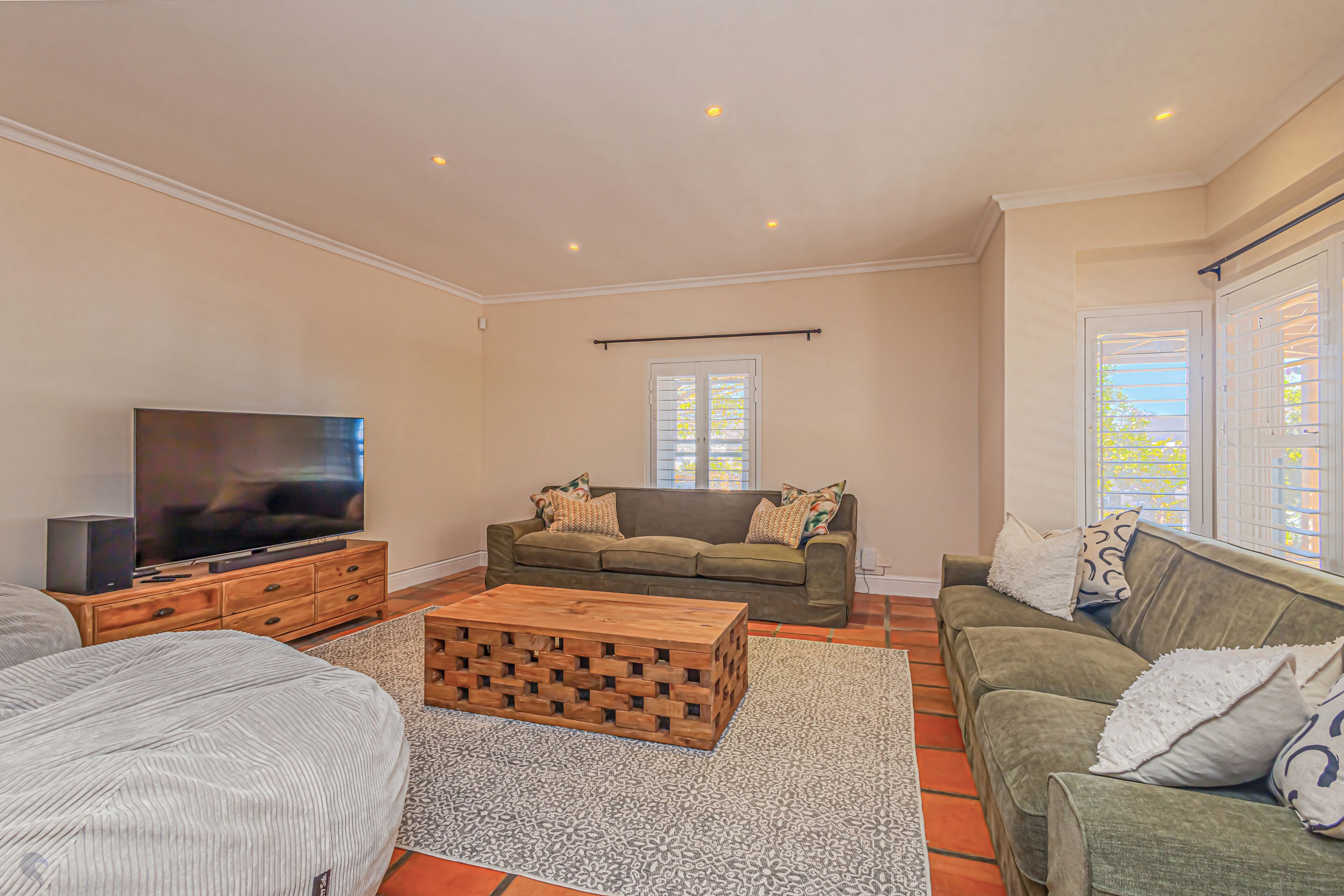 A living room with a TV, two sofas, a coffee table, and a patterned rug.