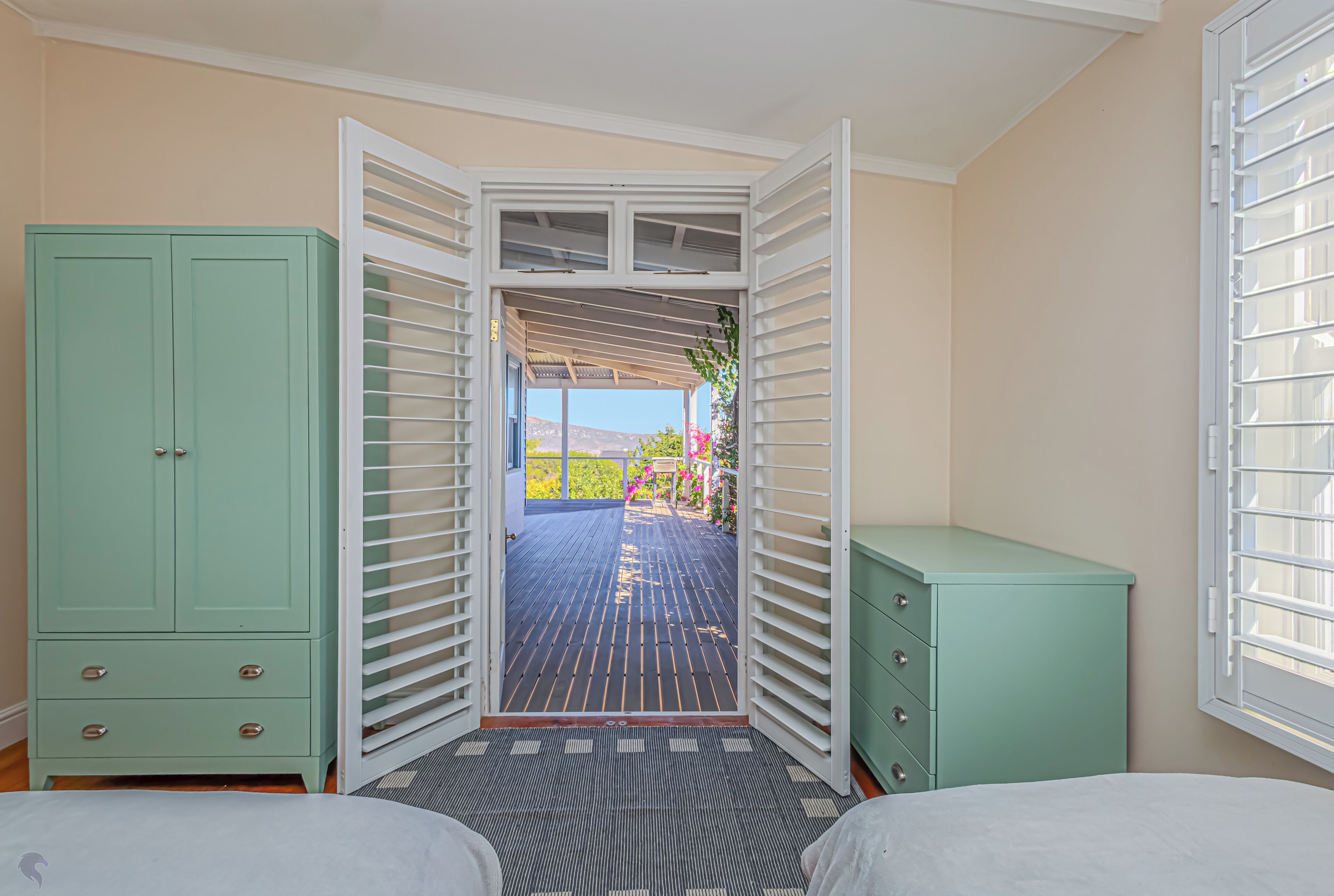 A bedroom with a bed, a wardrobe, and a door leading to an outdoor deck.