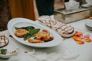 Pöydällä on leivonnaisia ja jälkiruokaa, ja pöytä on peitetty valkoisella pöytäliinalla.