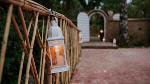 A pathway with a lantern hanging on a bamboo fence. - Le Bled (Marrakech)