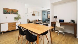 A modern office space with a wooden table, black chairs, a desk with a computer, and a sofa in the background. - RARE FIND! Modern 2 Bdrm, 2 Bath, 1 Car in Central Sydney (City of Sydney)