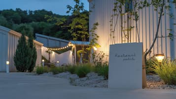 A restaurant sign in a garden setting with a pathway leading to a building.