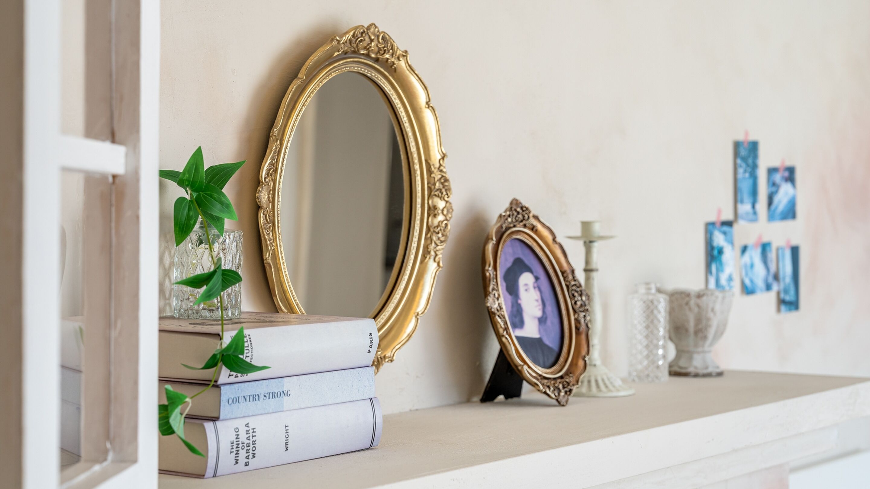 Een boekenplank met boeken, een spiegel en decoratieve objecten.