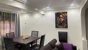 Uma área de refeições com mesa e cadeiras, um quadro na parede e vista para o exterior.