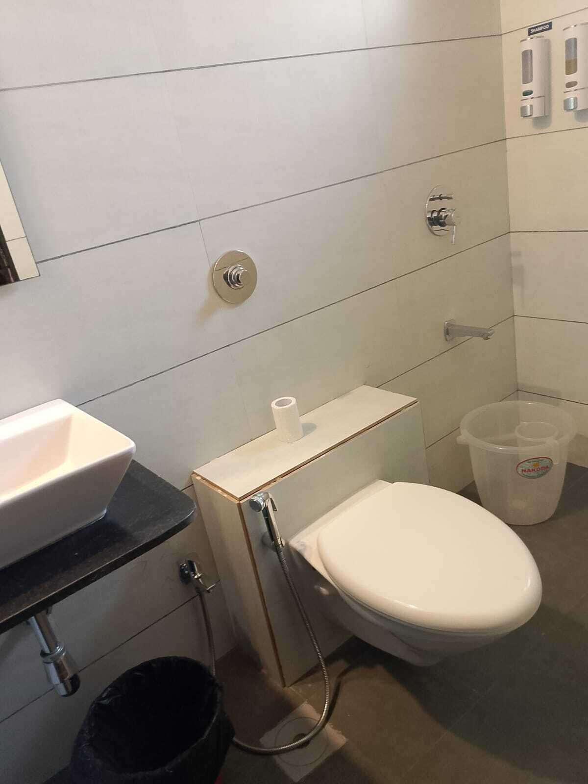 Une petite salle de bain avec des toilettes blanches, un lavabo et une douche.