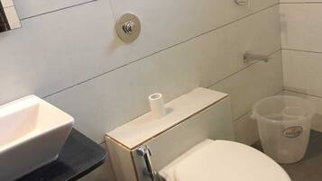Une petite salle de bain avec des toilettes blanches, un lavabo et une douche.