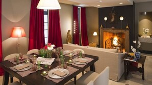 Un comedor con una mesa para cuatro, un sofá, una chimenea y una lámpara.
