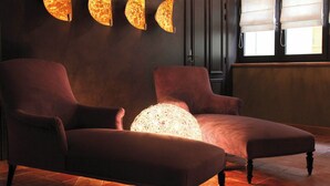 Una habitación con dos sillones, una lámpara esférica grande y tres lámparas de pared.