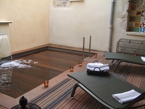 A spa area with a wooden hot tub, lounge chairs, and candles. - Gîte Étoiles d’Orion (Marsolan)