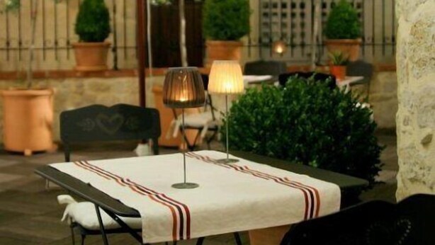Un área de comedor al aire libre con una mesa, sillas, una sombrilla y plantas en macetas.