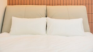 Een bed met hoofdeinde tegen een bakstenen muur.
