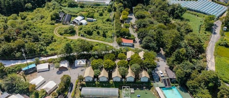 Vista aérea de una zona residencial con varias casas, una piscina y un invernadero.