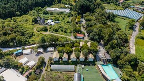 Vue aérienne d’un quartier résidentiel comprenant plusieurs maisons, une piscine et une serre.