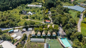 Vista aérea de una zona residencial con varias casas, una piscina y un invernadero.