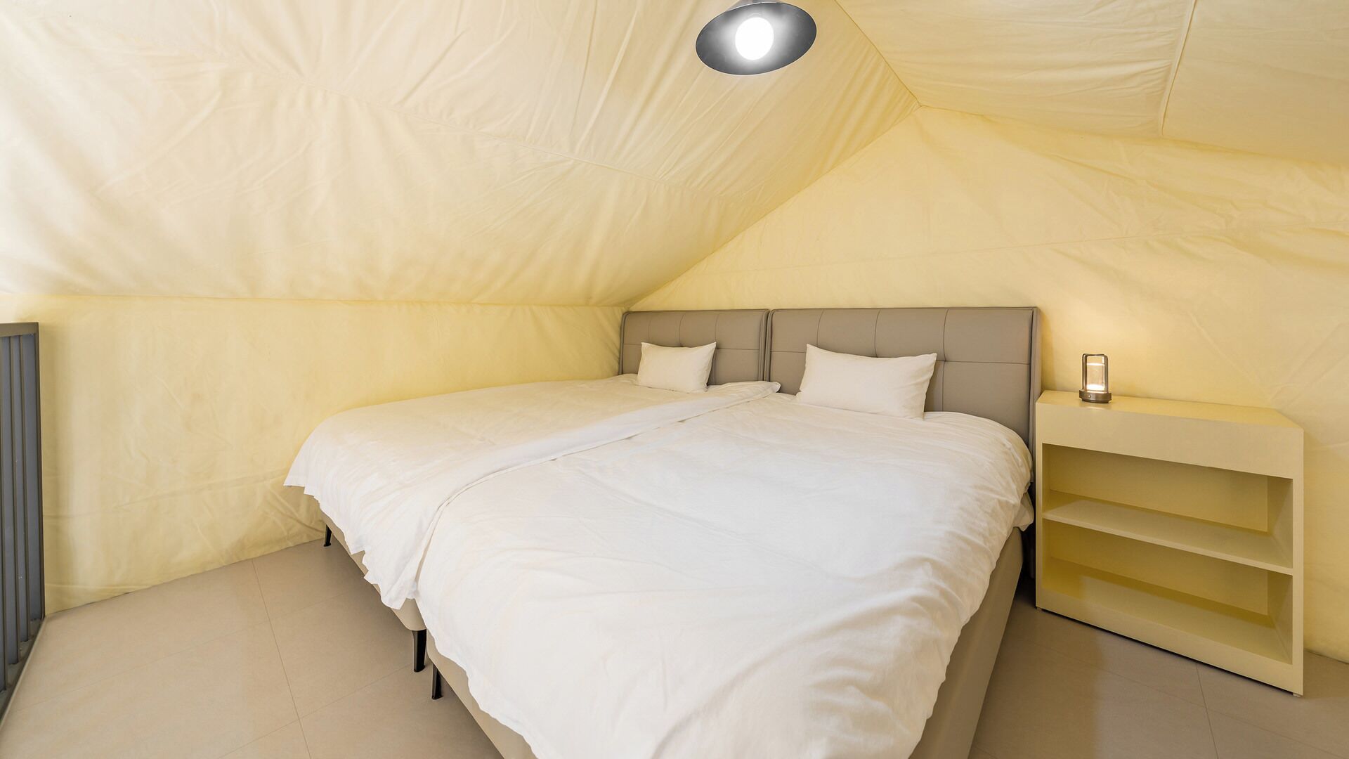 A bedroom with a single bed, a nightstand, and a lamp.