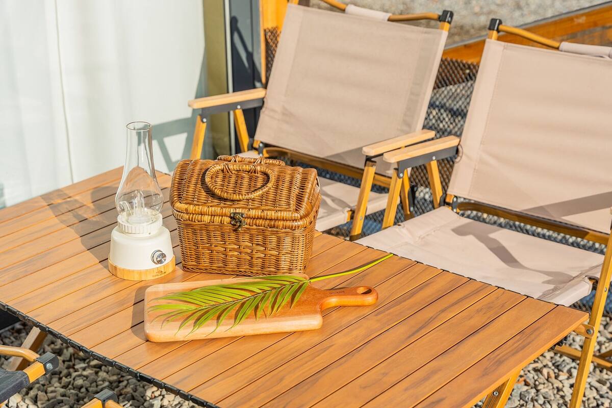 A wooden table with a portable gas stove, a wicker basket, and a rolling pin.
