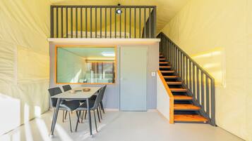 A room with a dining table, chairs, a staircase, and a door.