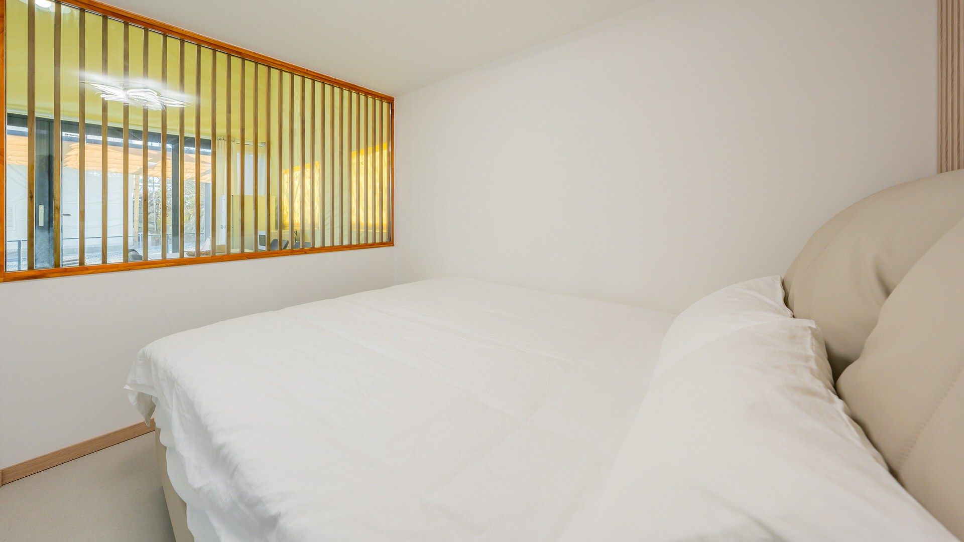 A bedroom with a bed, a window with blinds, and a view of the outside.