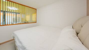 A bedroom with a bed, a window with blinds, and a view of the outside.