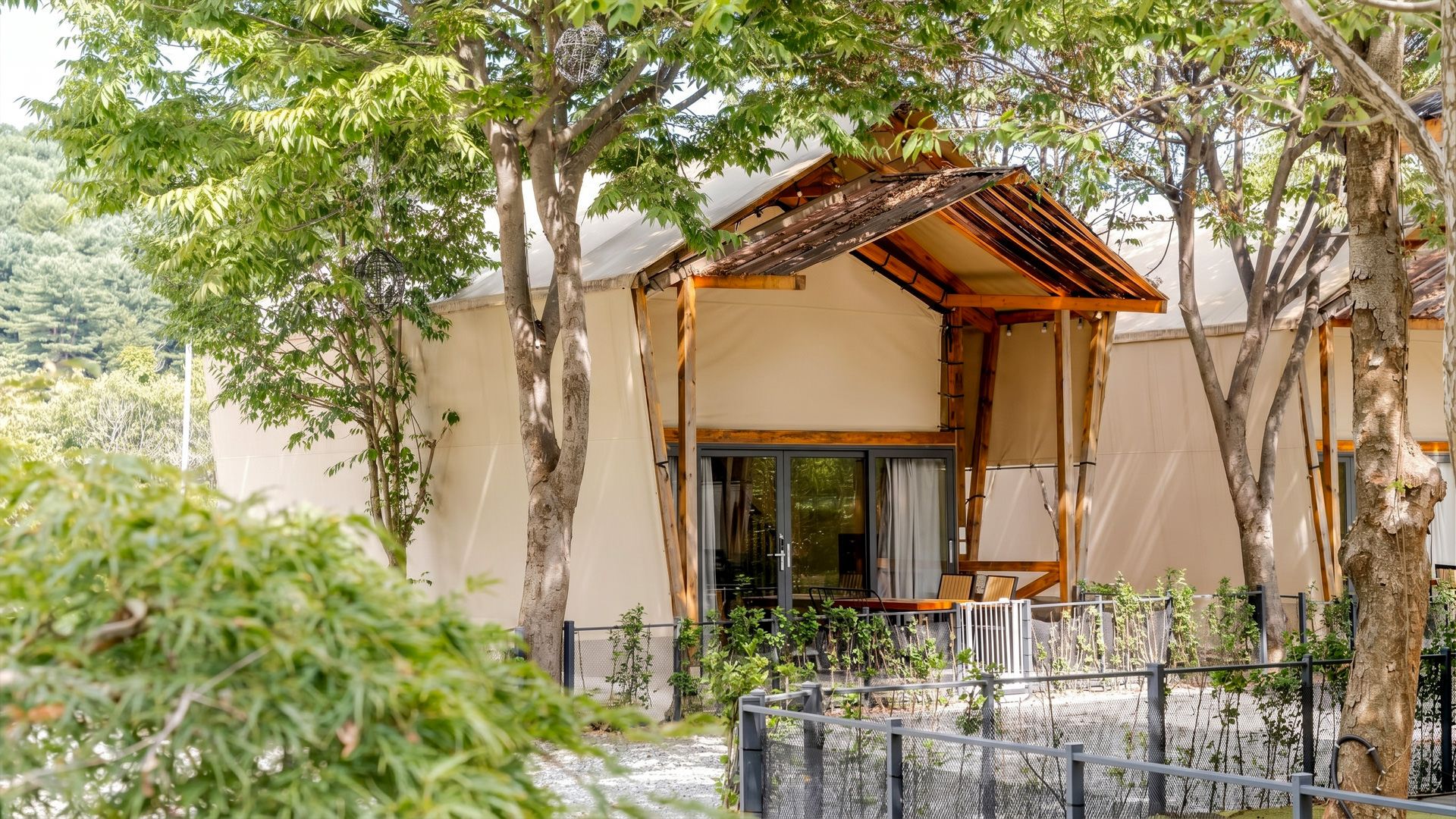 A traditional Japanese-style building with a wooden structure, a sliding glass door entrance, and a fenced garden area.