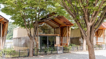 A wooden cabin with a covered porch, large windows, and a fenced garden area.