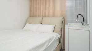 A bed with a headboard, a bedside table, and a sink with a faucet. - Gapyeong High Mong Glamping & Camping (Gapyeong)