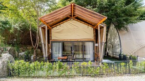 A wooden cabin with a pitched roof, glass doors, and a table with chairs outside. - Gapyeong High Mong Glamping & Camping (Gapyeong)