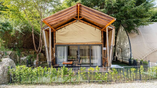 A wooden cabin with a pitched roof, glass doors, and a table with chairs outside. - Gapyeong High Mong Glamping & Camping (Gapyeong)
