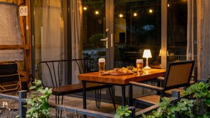 An outdoor dining area with a table set for two, two chairs, a lamp, and a plate of snacks. - Gapyeong High Mong Glamping & Camping (Gapyeong)