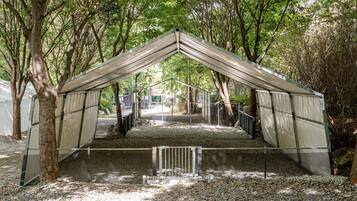 A covered outdoor area with a metal roof, surrounded by trees.