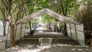 Un espacio al aire libre techado con metal, rodeado de árboles.