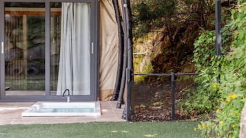 A modern outdoor area with a glass door, a small pool, and a garden with a fence.
