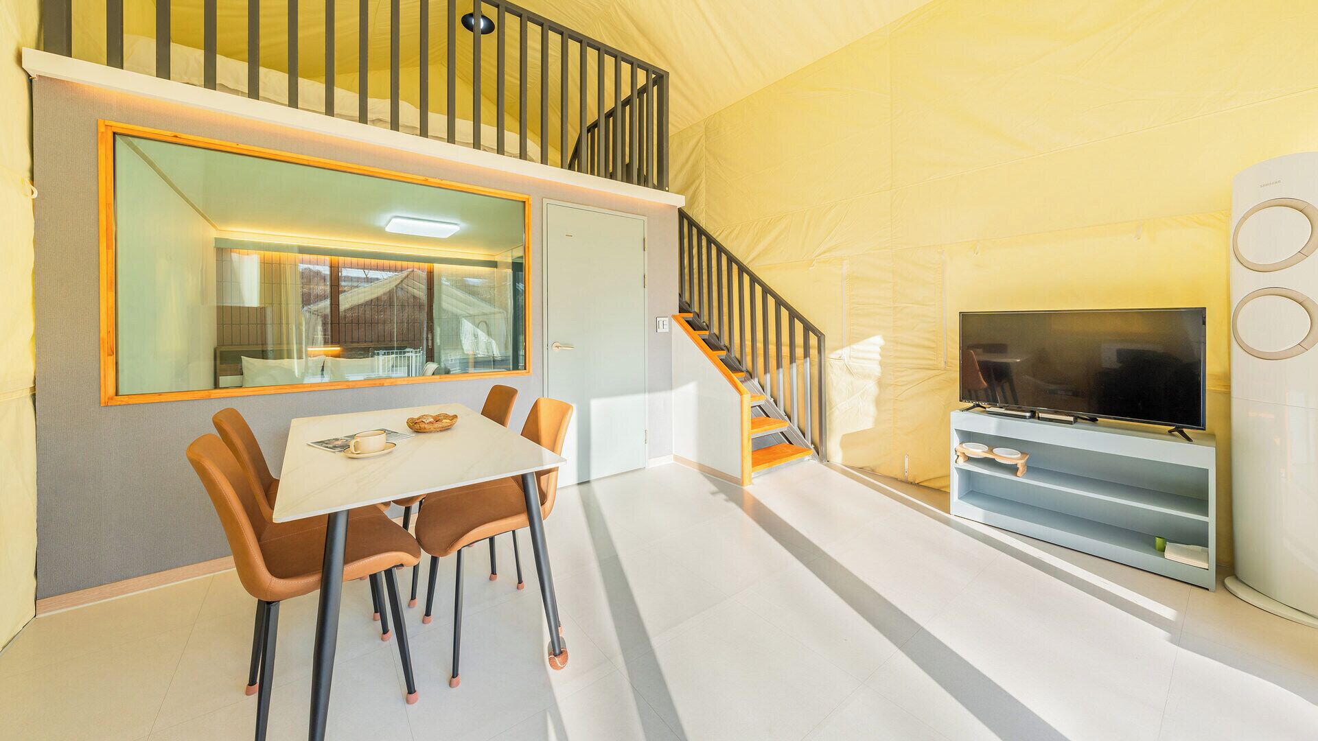 A modern interior with a dining area, a staircase, and a television.