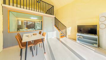 A modern interior with a dining area, a staircase, and a television.