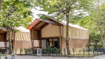 A bungalow-style accommodation with a pitched roof, large windows, and a covered outdoor area.