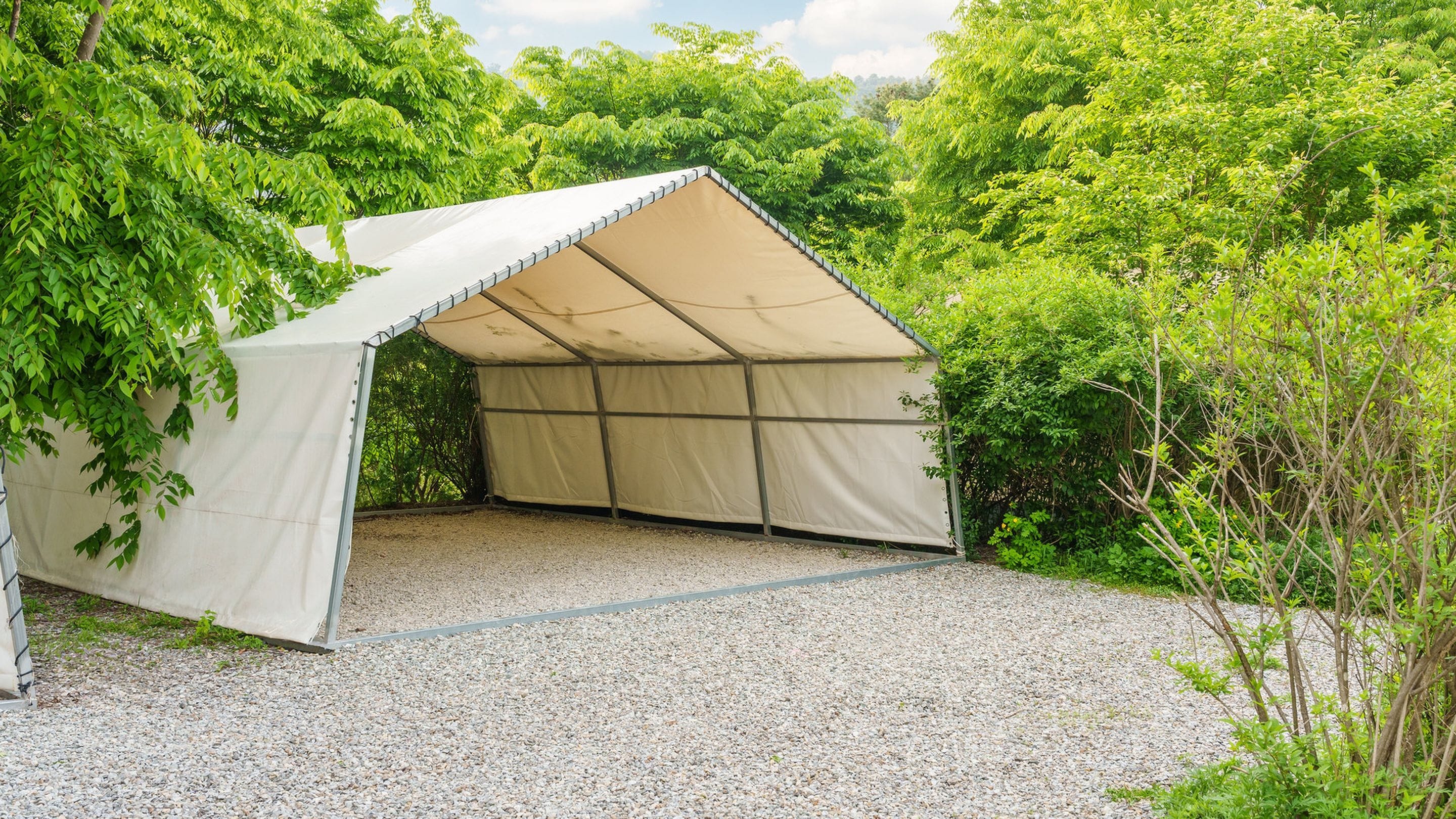 A tent-like structure with a gravel floor, surrounded by dense greenery.