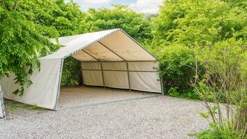 A tent-like structure with a gravel floor, surrounded by dense greenery.