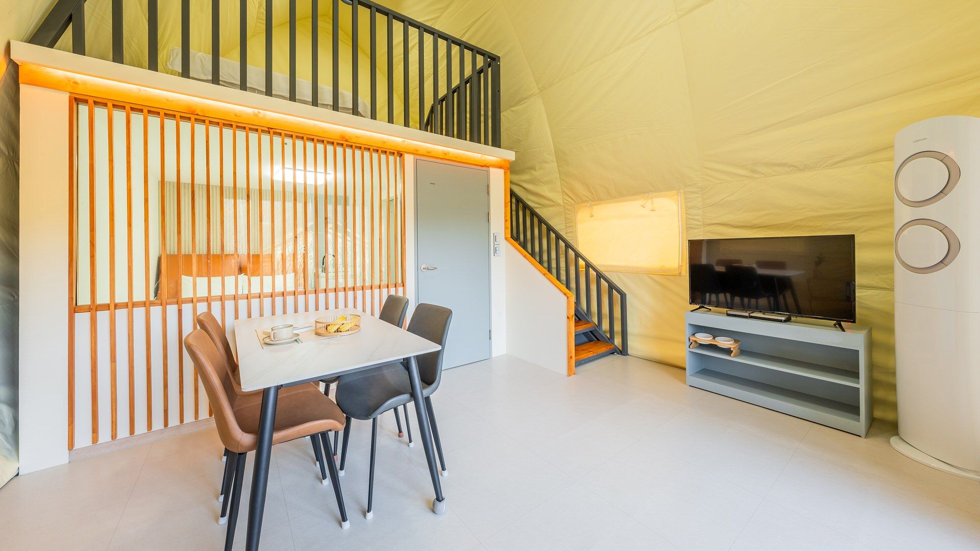 Een modern interieur met een eethoek, een trap en een televisie.
