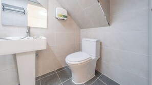 Een badkamer met toilet, wastafel en zeepdispenser.