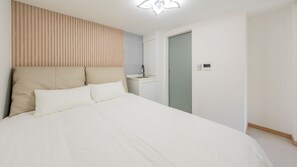 A bedroom with a bed, a nightstand, a wall-mounted light, and a door. - Gapyeong High Mong Glamping & Camping (Gapyeong)