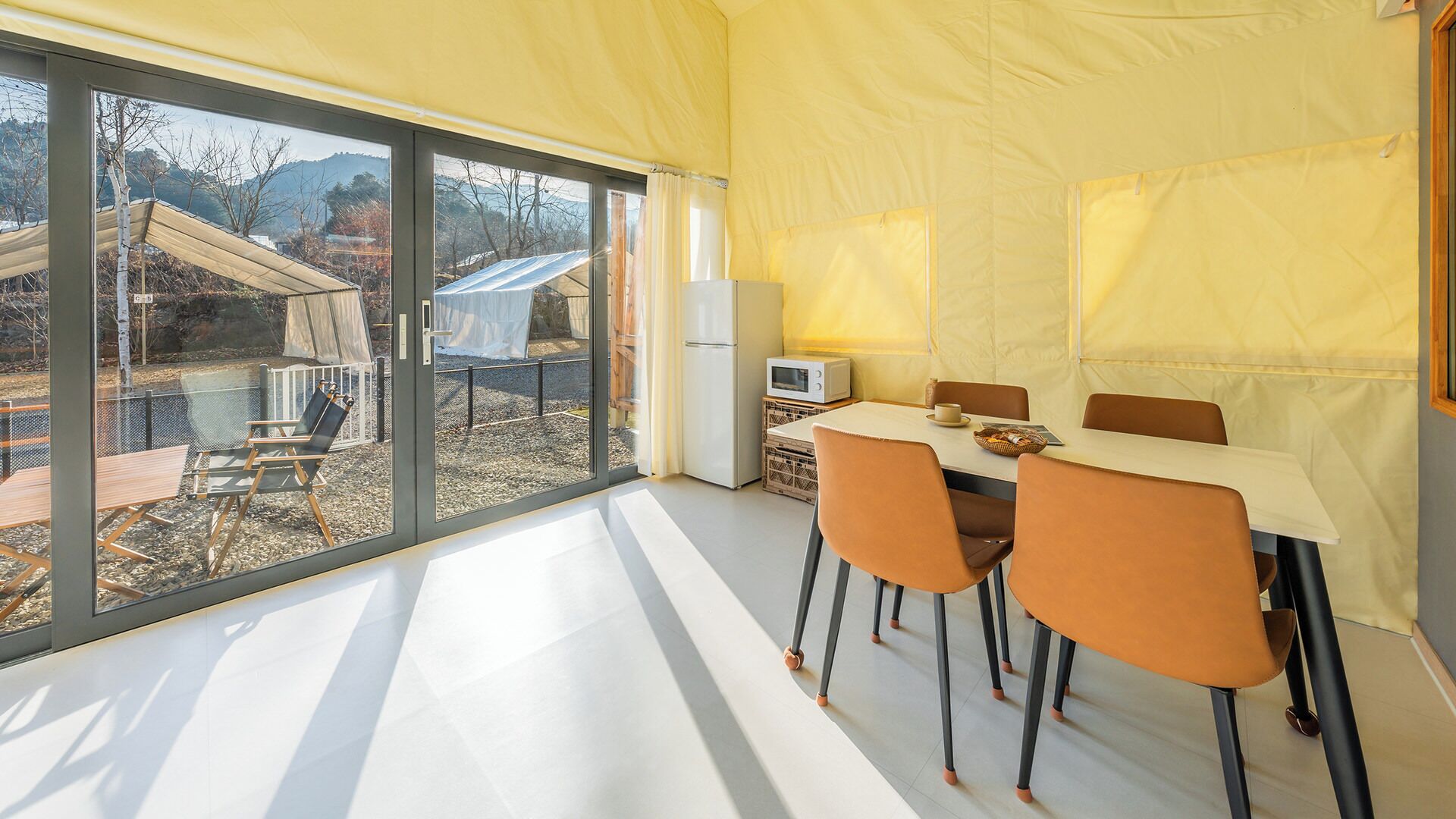 A modern dining area with a table, chairs, and a view of the outdoors.