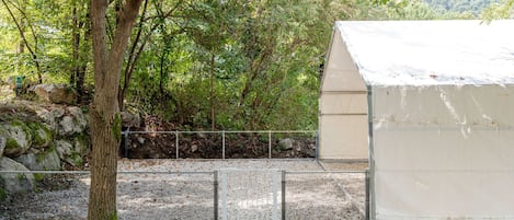 A covered outdoor area with a gravel path, a metal fence, and a building with a white roof.