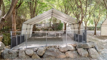 A covered outdoor area with a metal fence, surrounded by rocks and trees.