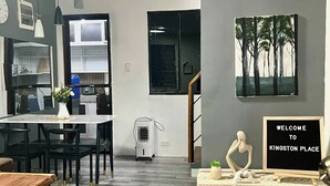 A modern kitchen with a dining area, a wall-mounted sign reading 'Thankful Grateful Blessed,' and a welcome sign for 'Kingston Place.' - Cozy Holiday Home in San Pablo City for Groups of 8-10 (San Pablo)