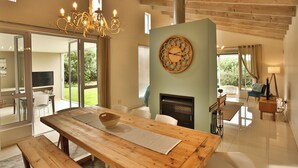A spacious dining area with a wooden table and benches, a fireplace, and a view of the outdoors. - La Maison, Langebaan 6-sleeper (Langebaan)