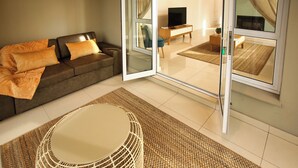 A modern living room with a sofa, a coffee table, and a television. - La Maison, Langebaan 6-sleeper (Langebaan)