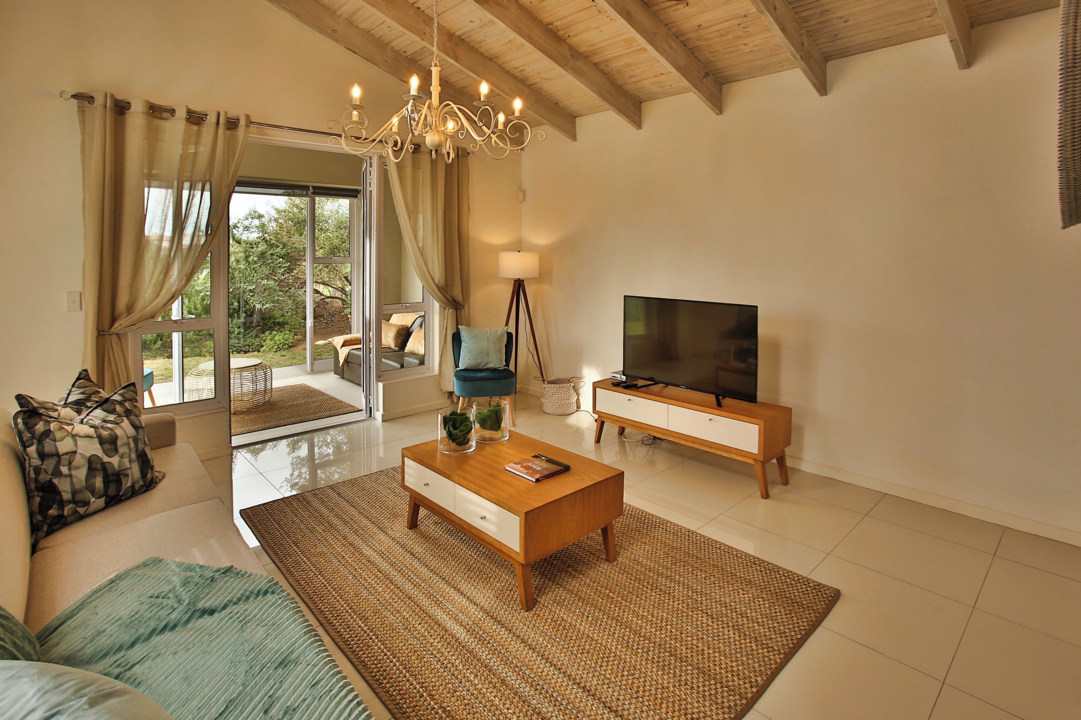 A modern living room with a sofa, coffee table, TV, and a view of the outdoors.
