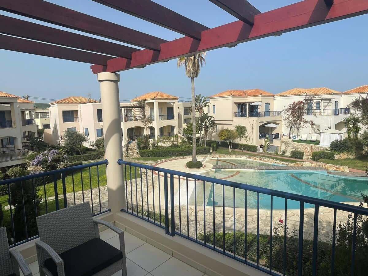 A balcony with a view of a swimming pool and multiple buildings in the background.