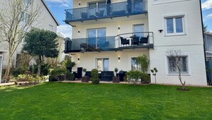 A two-story building with a balcony, a garden, and a clear sky. - Black Forest vacation apartment with dream terrace (Freudenstadt)