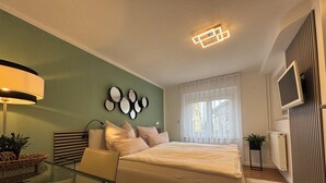 A modern bedroom with a bed, bedside table, lamp, and decorative mirrors on the wall. - Black Forest vacation apartment with dream terrace (Freudenstadt)
